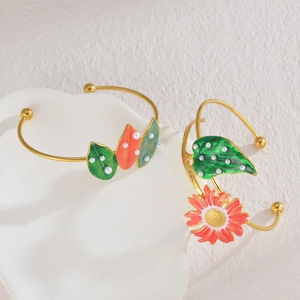 Detail of floral enamel gold open bracelets featuring green leaves and daisy with white pearls