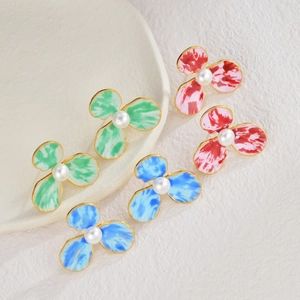 Détail macro de boucles d'oreilles fleurs tricolores avec bords dorés et perles centrales