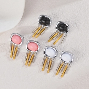 Close-up of geometric fringe earrings set with colorful stones on a stone background