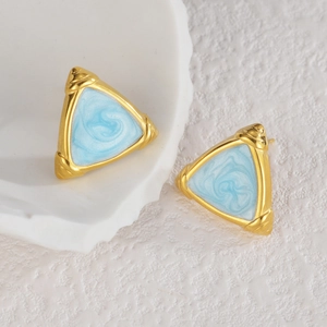 Detail of triangle stud earrings with gold frame and light blue marble inlay on white stone