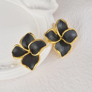 Détail de boucles d'oreilles fleurs 3D noir mat avec bords dorés et pétales texturés