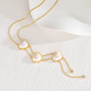 Elegante collana a serpente dorata con tre ciondoli a cuore in madreperla