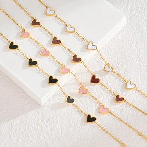 Détail de chaînes dorées avec des pendentifs en forme de cœur blanc, rouge, rose et noir