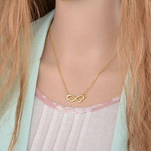 Gold infinity necklace with interlocking hearts and crystal accent shown on a model