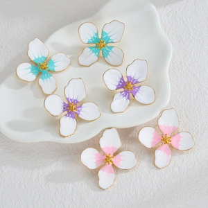 Détail de boucles d'oreilles fleurs en émail avec pétales dégradés et cœur doré