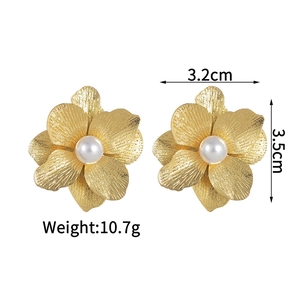 Close-up of brushed gold layered flower earrings with a white pearl center detail