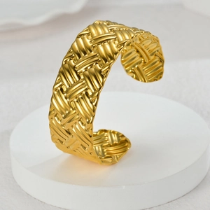Vintage wide braided texture open bangle in gold finish on a minimalist display stand