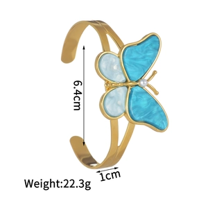 Detail showing 6.4cm inner diameter and marble butterfly charm on a golden bangle