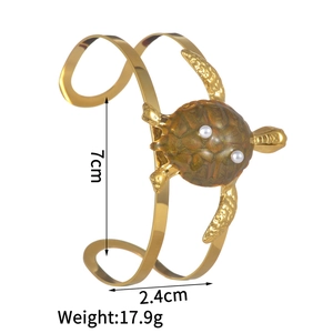 Macro detail of golden double-line turtle bangle with brown resin shell and white pearls
