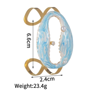 Detailed view of wide gold cuff bracelet featuring blue enamel and size measurements