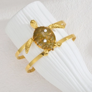 Detail of golden double-line turtle bracelet with olive green shell and pearls