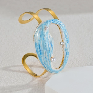 Detail of golden stainless steel bangle with blue marble enamel and pearl accents