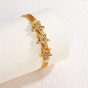 Gold mesh chain bracelet with three sparkling rhinestone star charms on white pedestal