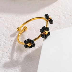 Vue détaillée d'un jonc ouvert doré orné de trois fleurs en perles noires
