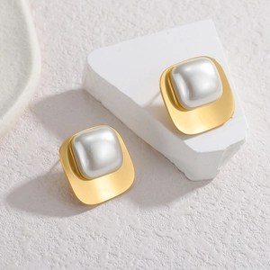 Boucles d'oreilles géométriques carrées en perles et finition dorée sur socle blanc