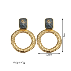 Dettaglio di orecchini a cerchio martellati placcati oro 18K con inserti in resina marmo