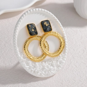 Orecchini a cerchio in oro 18K martellato su espositore con decoro di rose a rilievo
