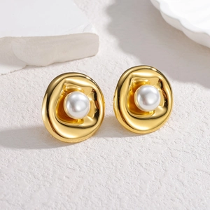 Boucles d'oreilles géométriques dorées avec perles et texture organique sur fond pierre