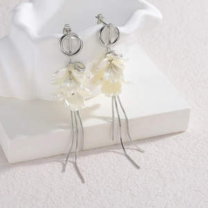 Elegant stainless steel tassel earrings with white floral petals on artistic display