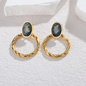 Vintage gold twisted rope earrings with starry blue stone on minimalist stone display