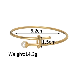 Detailed close-up of a gold adjustable open bangle with a white pearl and twist design