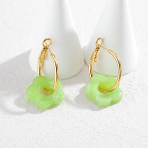 Détail macro de créoles plaquées or 18 carats avec breloques fleurs marbrées vert clair