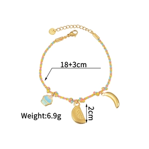 Colorful woven cord bracelet with gold fruit charms and cupcake pendant on white background