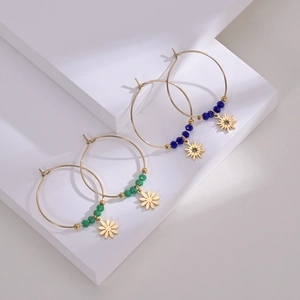 Detailed view of beaded hoop earrings with gold flower and star charms in green and blue