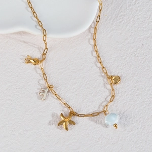 Collier marin doré avec breloques étoile de mer, coquillage et corail sur pierre blanche