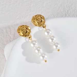 Elegant gold rose stud earrings with three vertical white pearls on a minimalist background