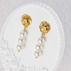 Vintage baroque angel relief earrings with triple white pearls on a display board