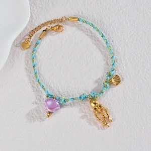 Detailed macro of 18k gold ocean starfish charm bracelet with woven blue and green cord
