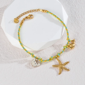 Macro detail of hand-woven bracelet with gold starfish, whale tail and seahorse charms