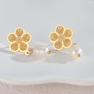 Elegant gold hollow flower earrings with white pearls on a minimalist white ceramic tray