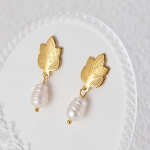 Detail of golden leaf earrings with baroque pearls showing textured veins and natural luster
