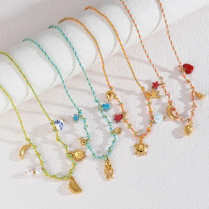 Collier marin tissé coloré avec breloques dorées comme des tortues sur colonne blanche