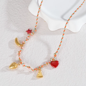 Détail d'un collier tressé coloré avec des breloques dorées en forme d'étoile et fruits