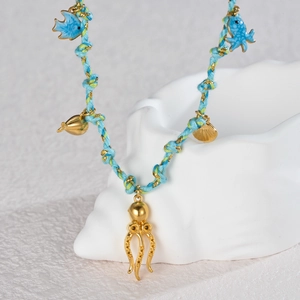 Détail du collier de mer tissé avec poulpe doré et breloques de poissons colorés