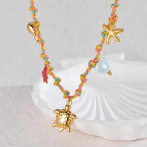 Détail des breloques de mer sur un collier en corde tressée colorée au style vacances