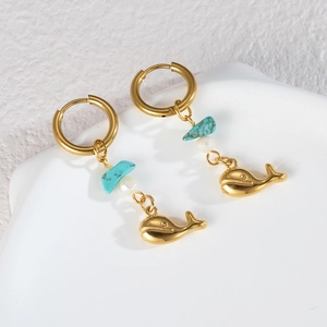 Détail macro de boucles d'oreilles dorées 18K avec pendentif baleine bleue et perle