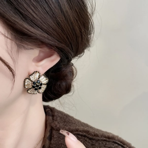 Detailed close-up of large 3D flower earrings with black and clear crystal zircon inlays