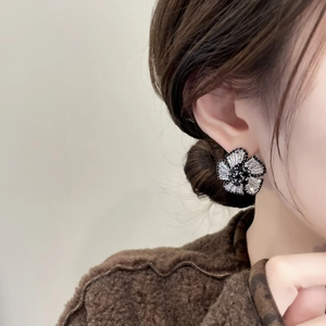 Close-up of elegant black flower stud earrings with sparkling crystals on female model