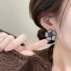 Elegant 3D flower stud earrings with black and white zircon stones worn by a model