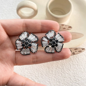 Macro shot of 3D floral earrings with baguette-cut zircons and black crystal accents