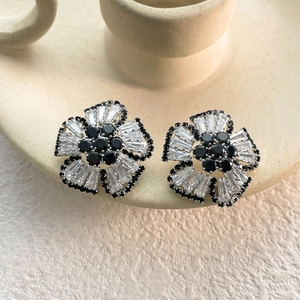 Macro detail of silver flower earrings with black and clear cubic zirconia stones