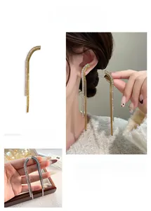 Macro detail of long curved earrings with shimmering crystals in gold and silver plating