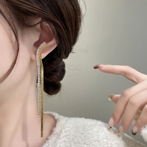 Close-up of golden multi-strand tassel earrings with sparkling rhinestones on model