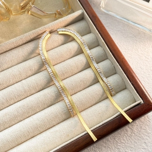 Macro detail of gold-plated tassel earrings with rectangular cubic zirconia accents