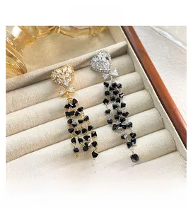 Detail of heart stud earrings with black bead tassels and bow on velvet display box