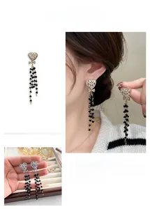 Detailed view of heart stud earrings with black crystal tassels and delicate bow accents